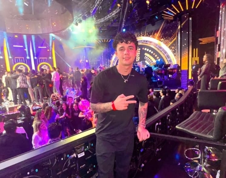 Hombre sonriente en evento musical con luces coloridas