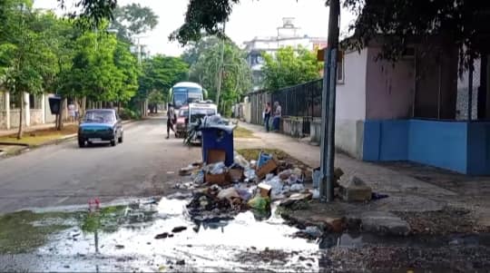 Calle con basura acumulada y autos pasando