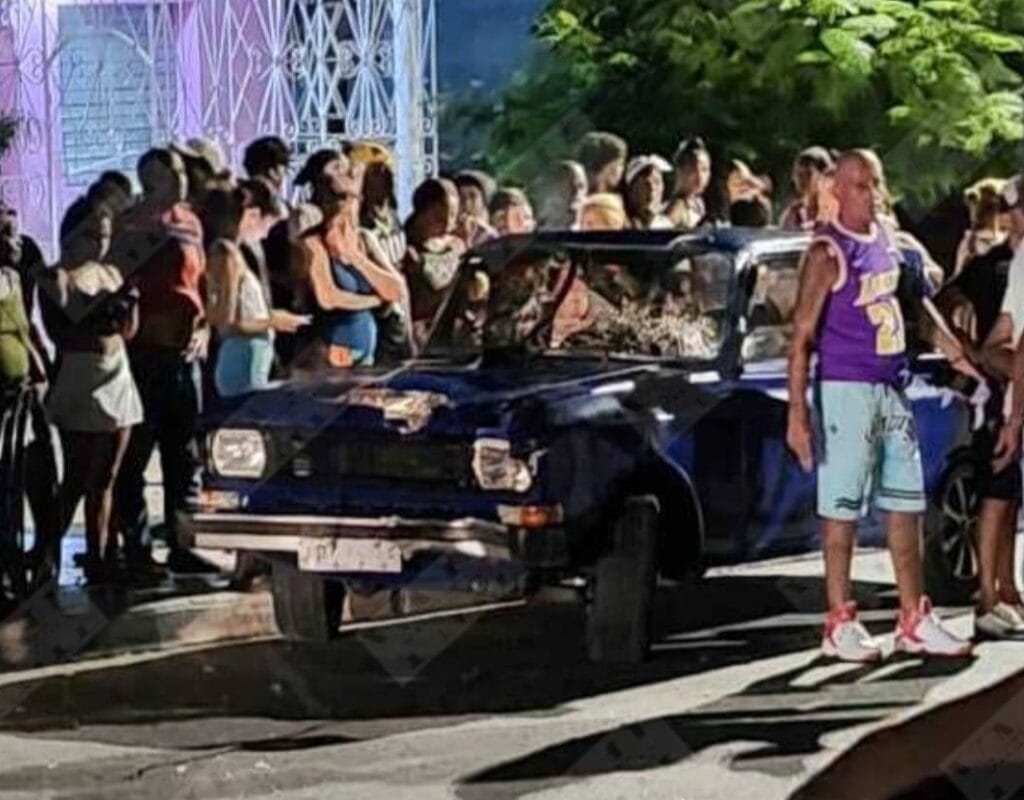 Coche antiguo y multitud en evento nocturno