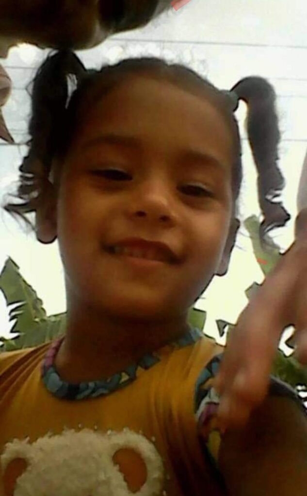 Niña sonriente con coletas y camiseta amarilla