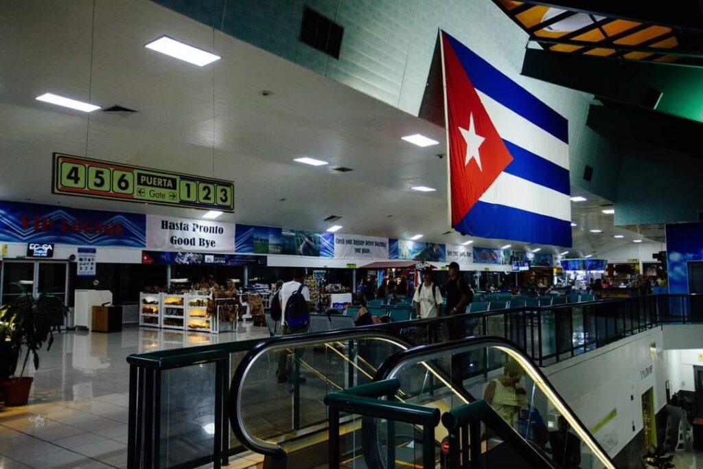 Aeropuerto con bandera cubana y señalización de puertas