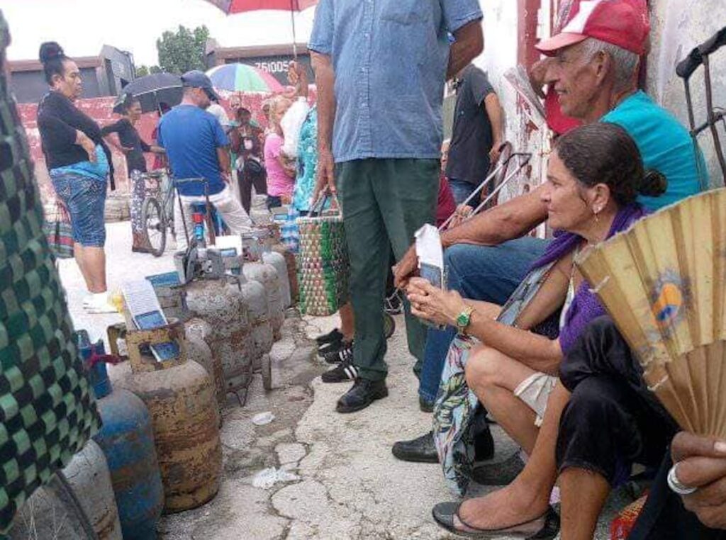 Gente esperando en cola con bombonas de gas