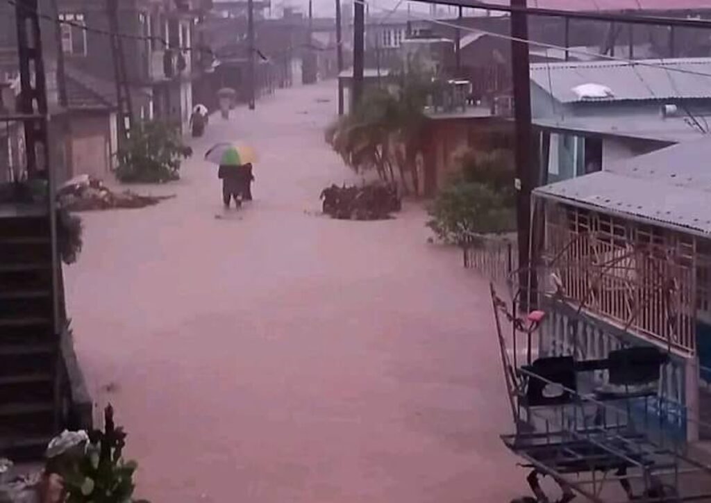 Calle inundada con personas caminando bajo la lluvia