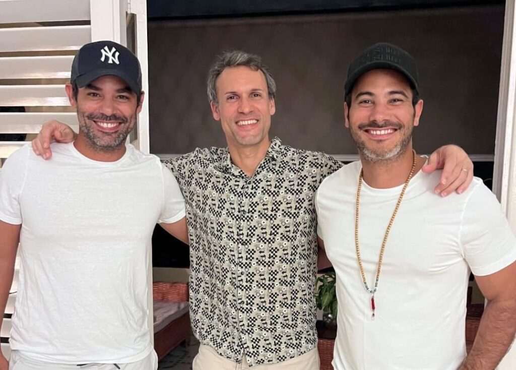 Tres hombres sonriendo juntos en interior