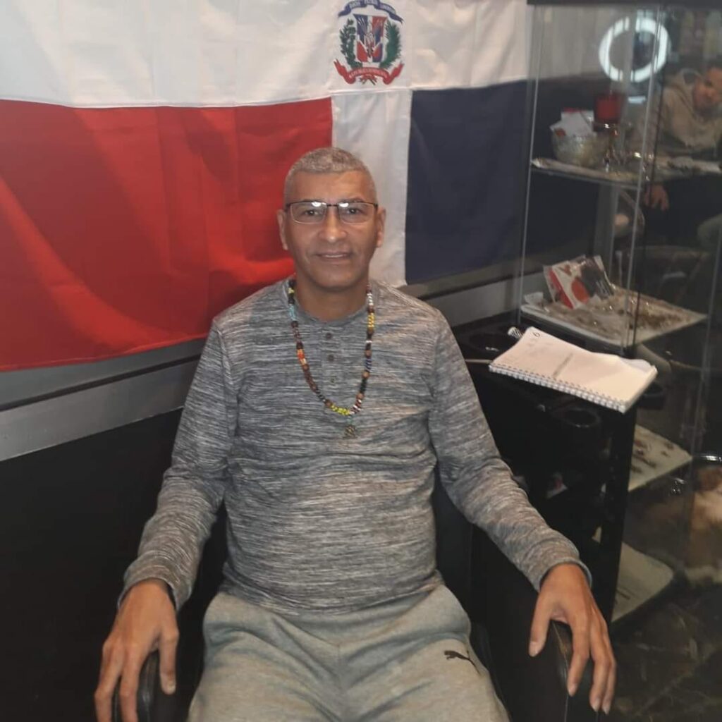 Hombre sentado frente a bandera dominicana