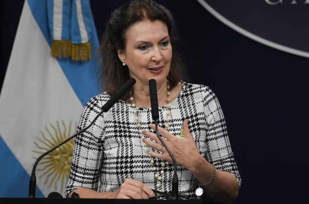 Mujer hablando en micrófono con bandera argentina