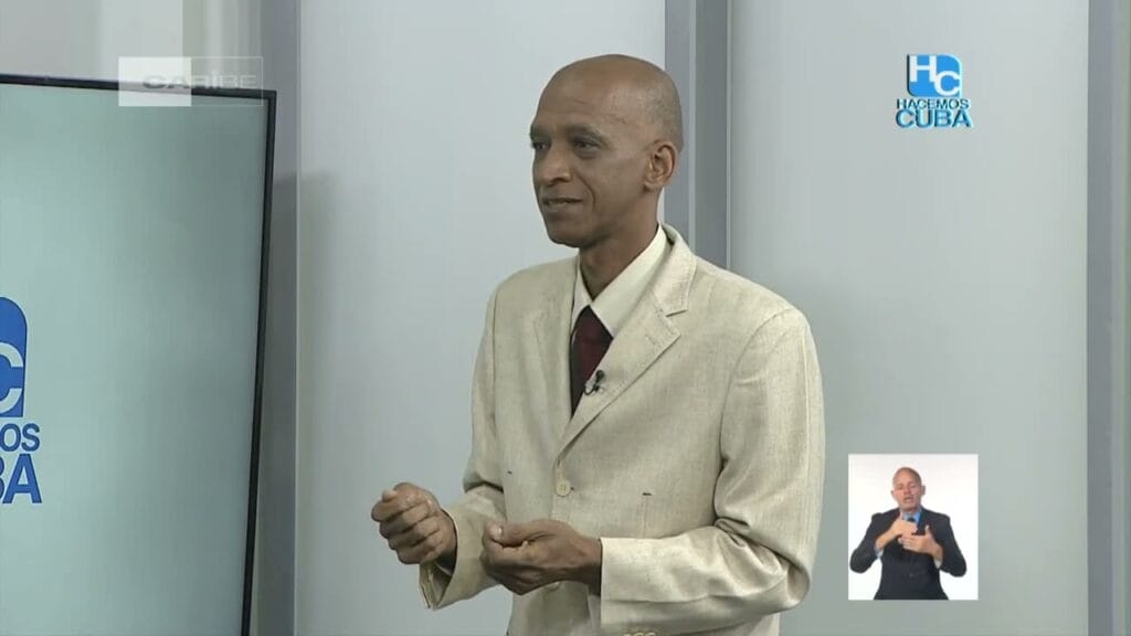 Hombre presentando en programa televisivo con intérprete de señas