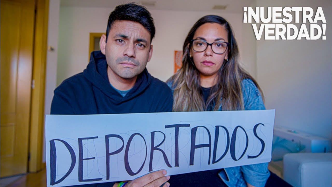 Pareja sosteniendo cartel 'Deportados' con expresión seria