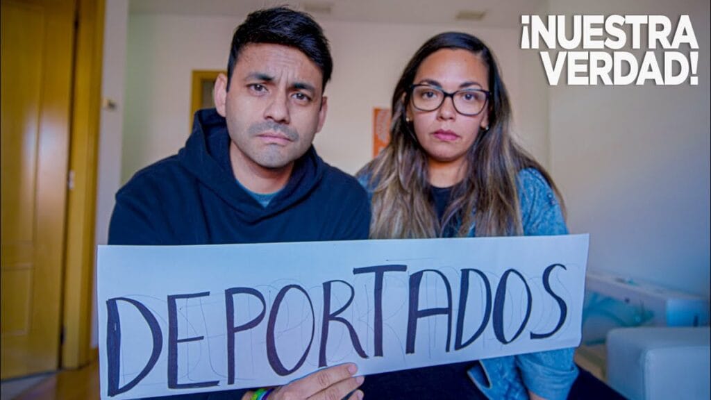 Pareja sosteniendo cartel 'Deportados' con expresión seria