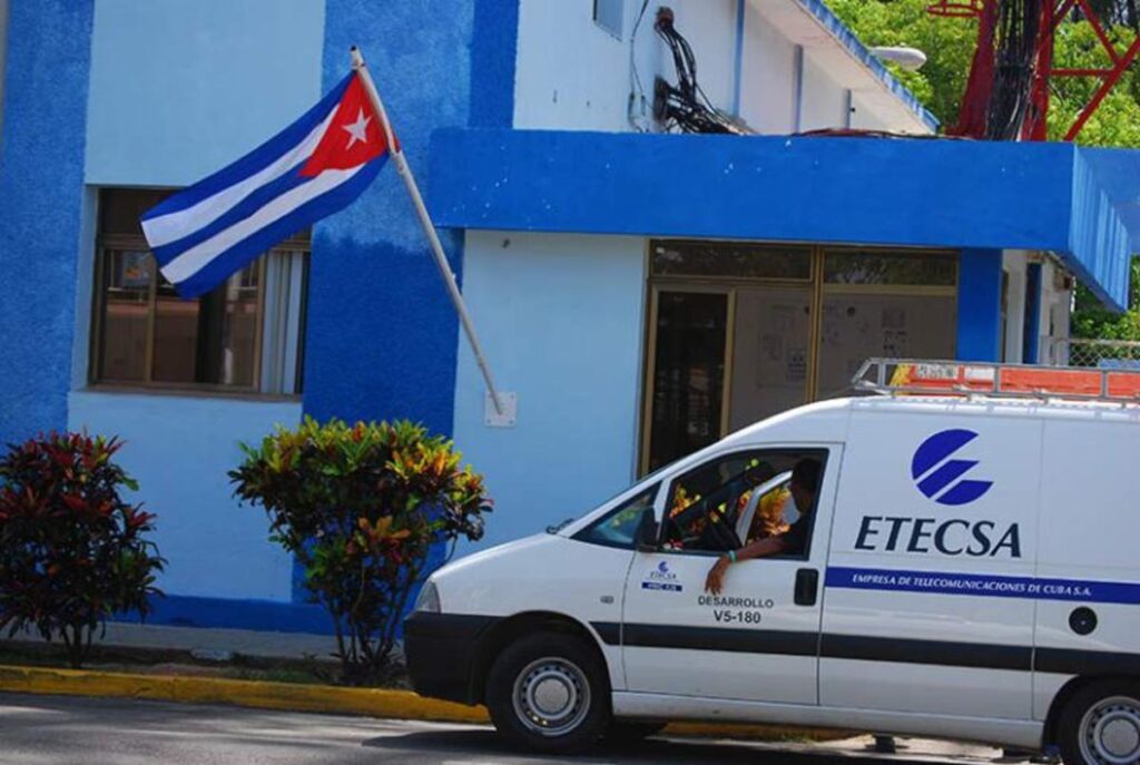 Furgoneta de ETECSA frente a edificio azul con bandera cubana
