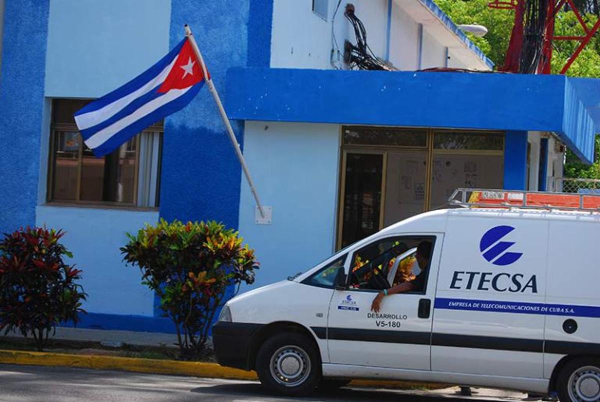 Furgoneta de ETECSA frente a edificio azul con bandera cubana