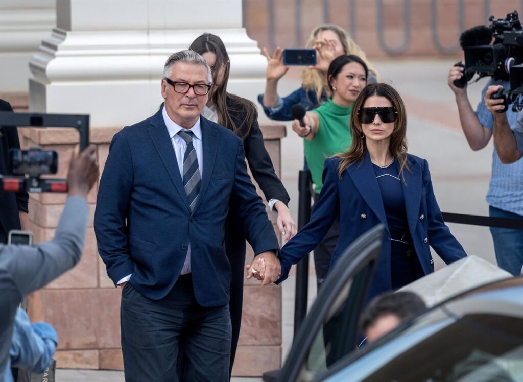 Pareja tomados de la mano saliendo, rodeados de prensa