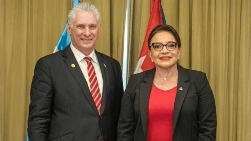 Dos diplomáticos sonriendo en evento formal.