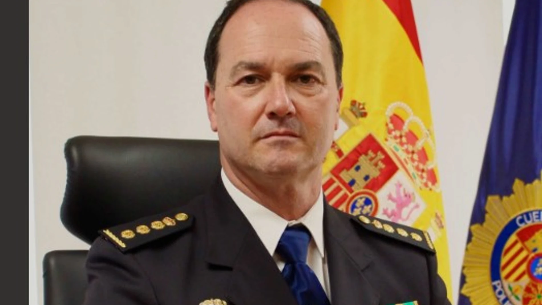 Hombre en uniforme con insignias, ante banderas de España