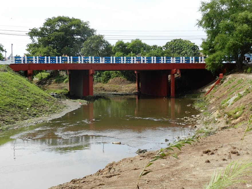 Puente rojo sobre río con barandilla azul