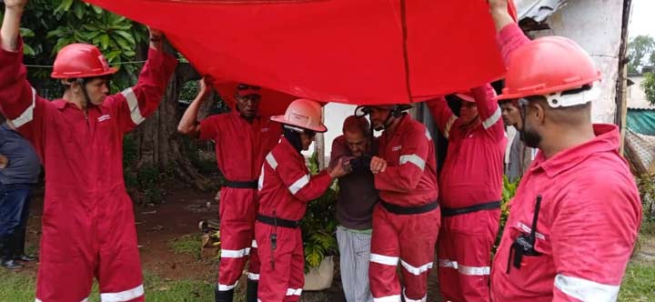 Trabajadores en uniforme rojo levantando lona grande