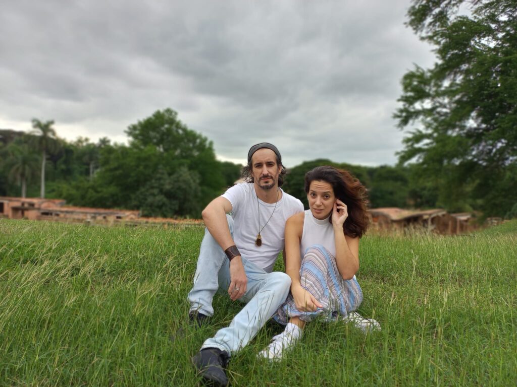Pareja sentada en campo verde con cielo nublado