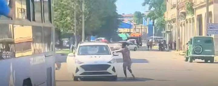 Persona empujando coche averiado en calle