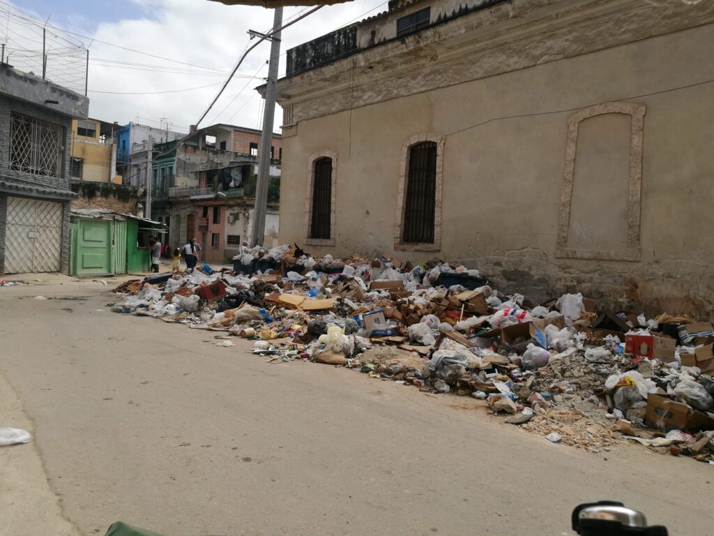 Calle con montones de basura y edificios deteriorados