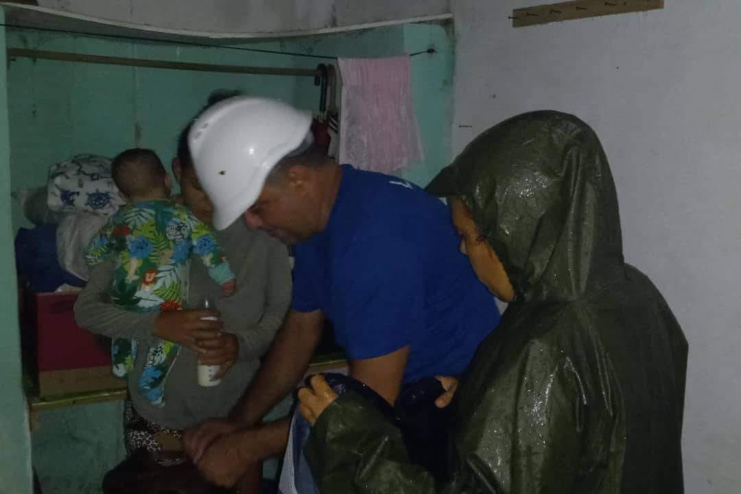 Gente en habitación con capas de lluvia y casco