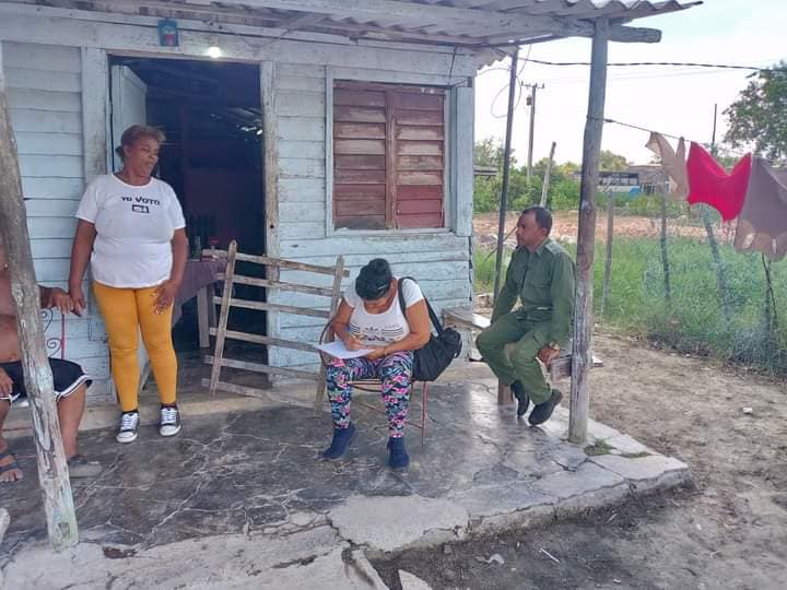 Tres personas frente a casa rural, una leyendo