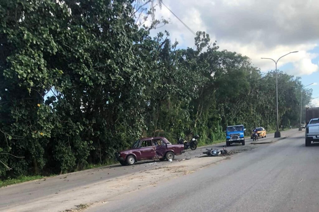 Coche viejo accidentado al lado de carretera arbolada