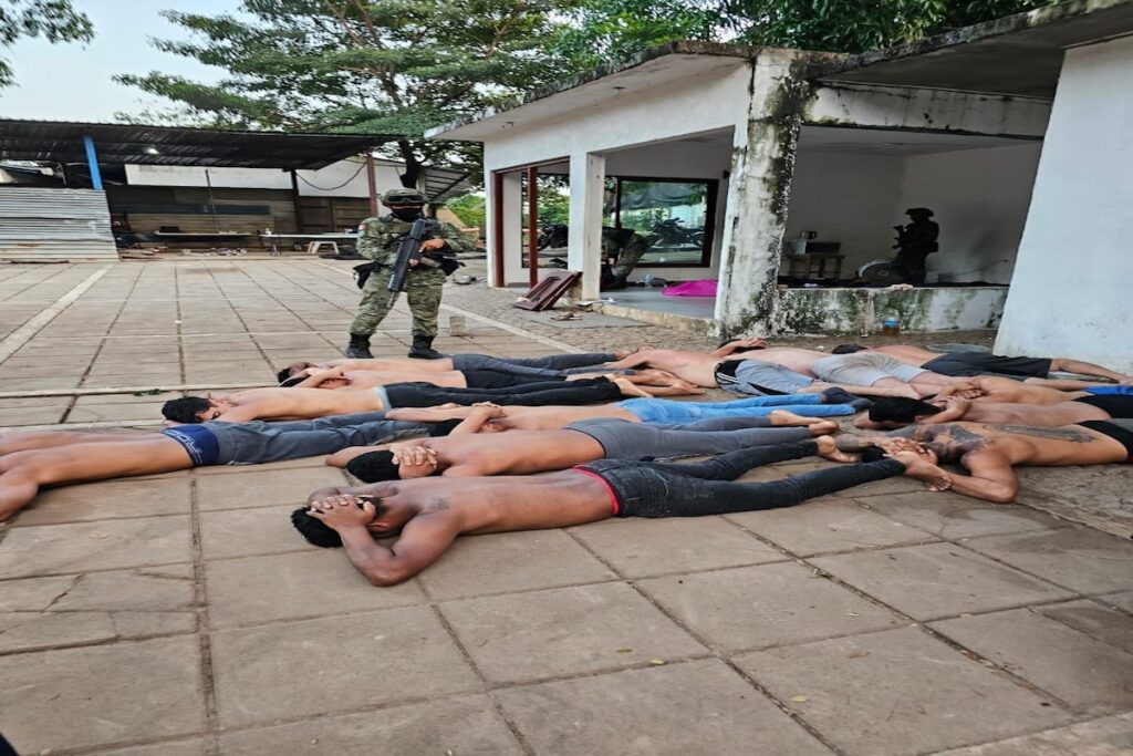 Soldado vigilando a hombres tumbados en fila