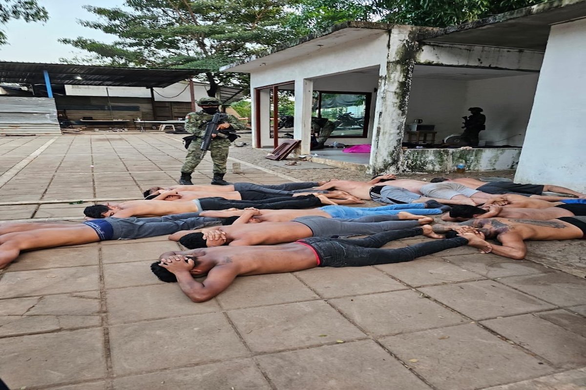 Soldado vigilando a hombres tumbados en fila