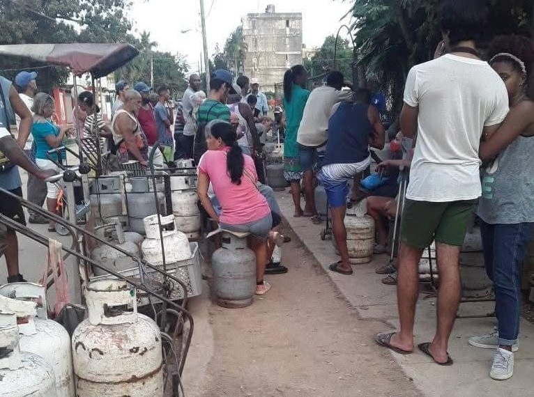 Personas esperando en fila con cilindros de gas