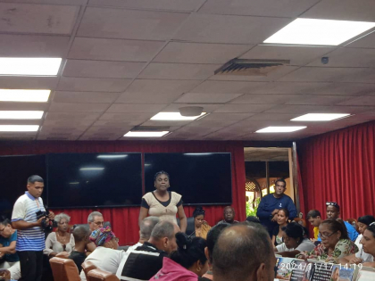 Gente reunida en evento interior con cortinas rojas