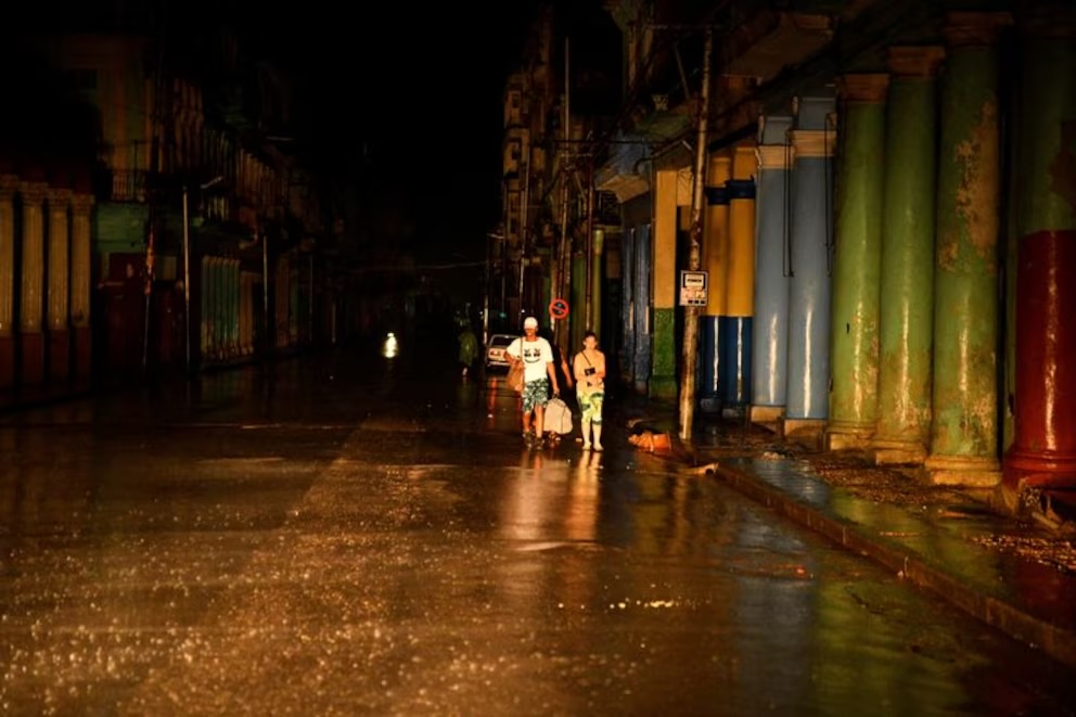 Calle mojada de noche con personas y edificios coloridos