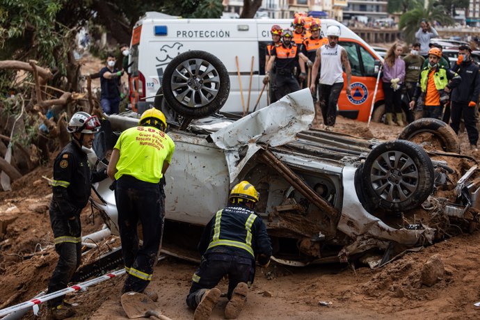Rescatistas trabajando en coche volcado tras desastre