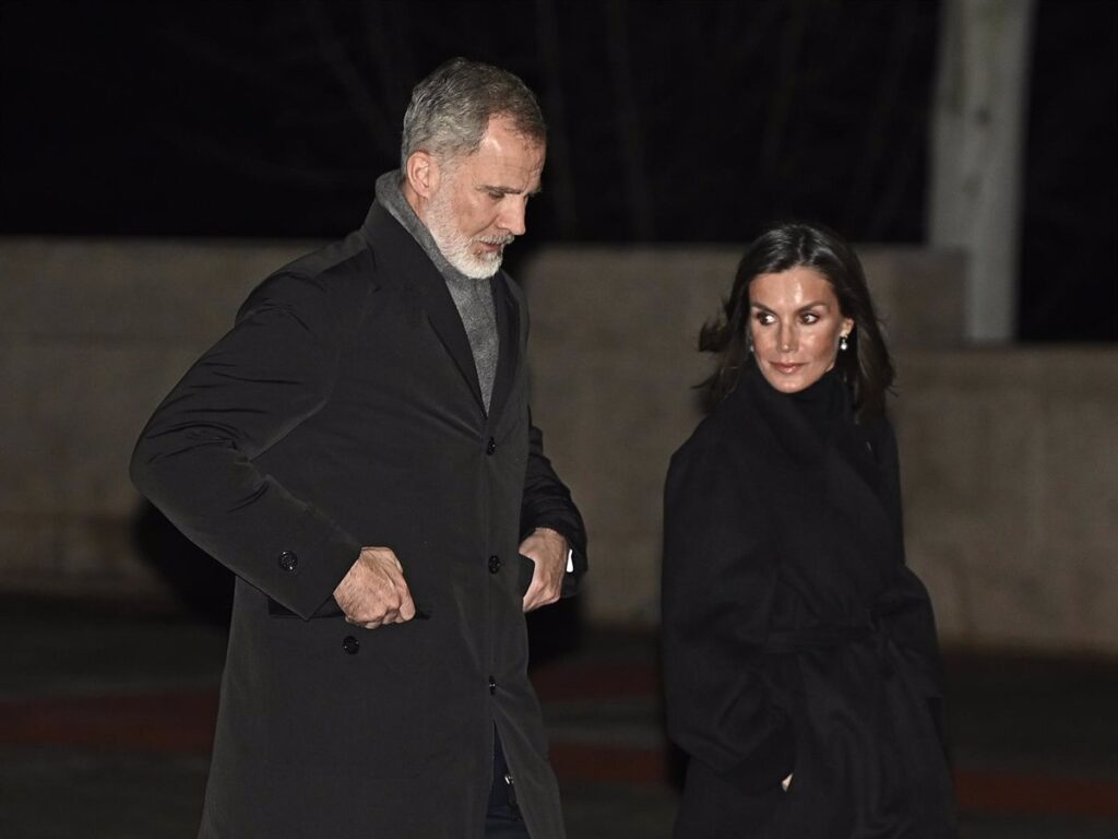 Pareja caminando de noche con abrigos elegantes
