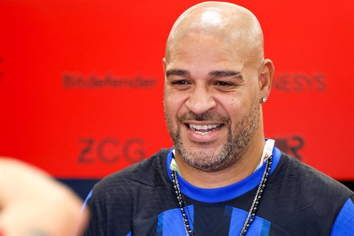 Hombre sonriente calvo en evento con fondo rojo