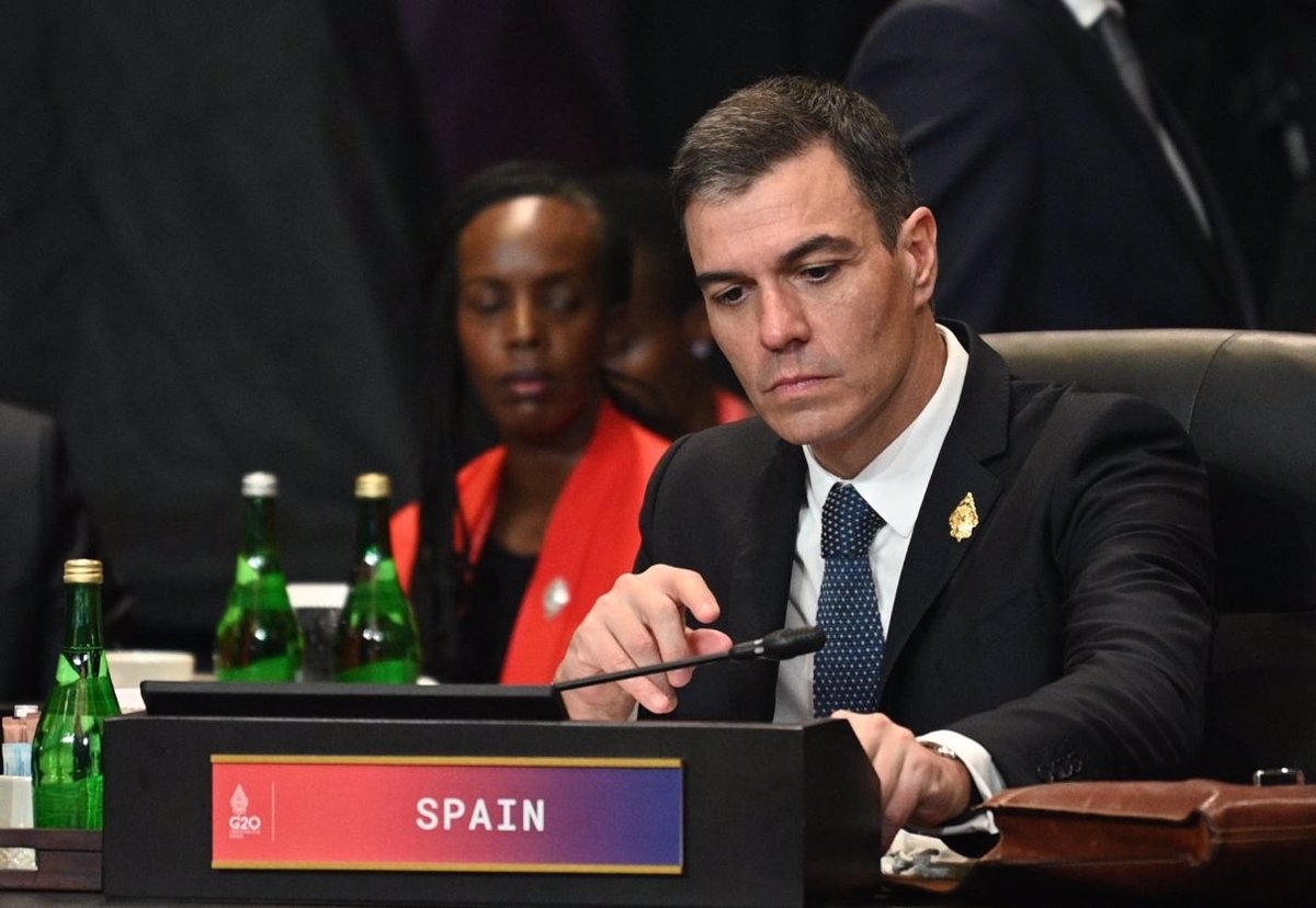 Hombre serio en reunión G20 con cartel de España