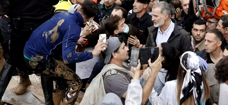 Hombre cubierto de barro junto a multitud con móviles