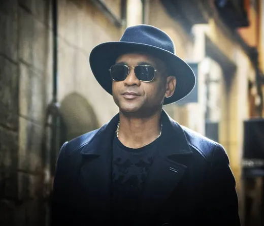 Hombre con sombrero y gafas en calle empedrada