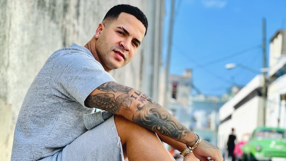 Hombre con tatuajes posando en calle urbana