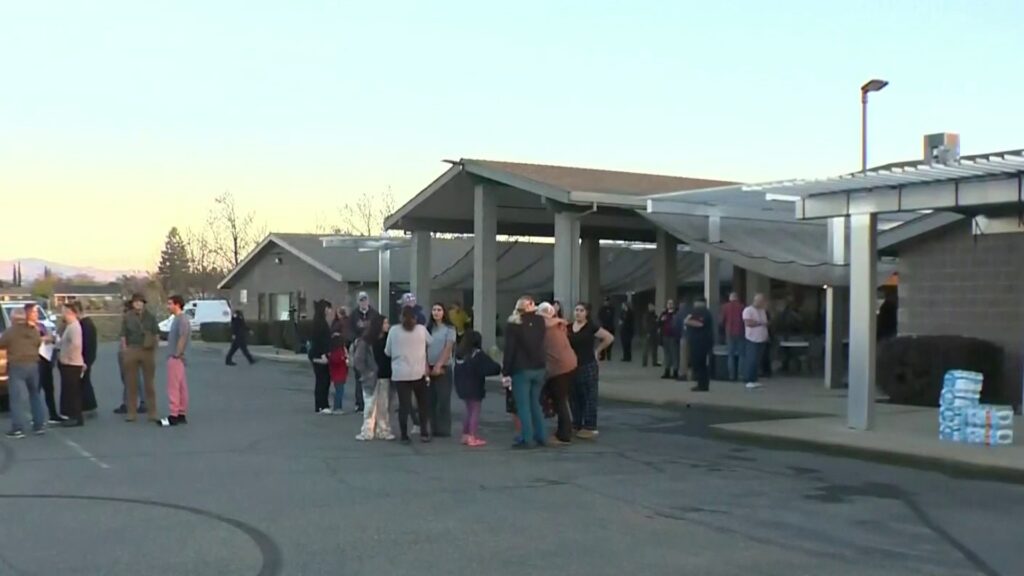 Personas reunidas en exterior de edificio al atardecer