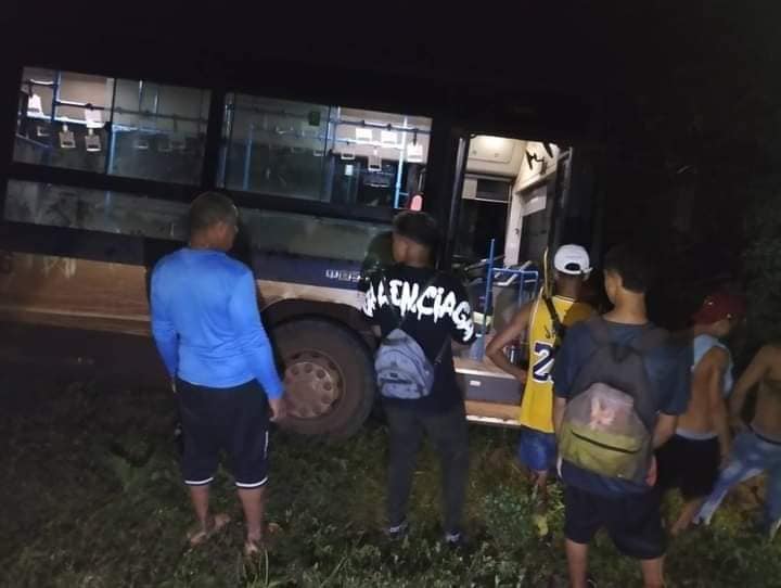 Personas subiendo a autobús nocturno en zona rural