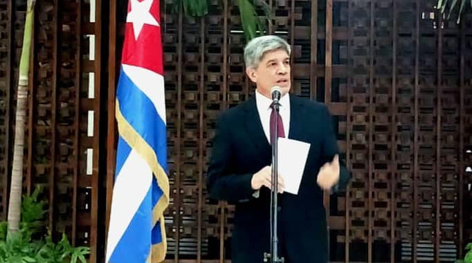 Hombre hablando en micrófono con bandera cubana