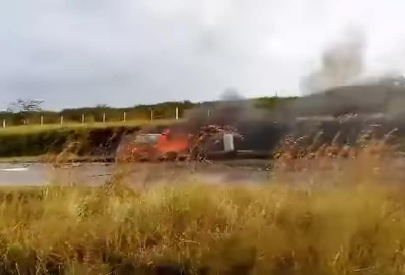 Coche rojo emitiendo chispas en carretera