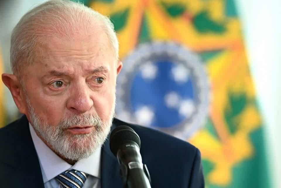 Hombre mayor hablando en micrófono con bandera detrás