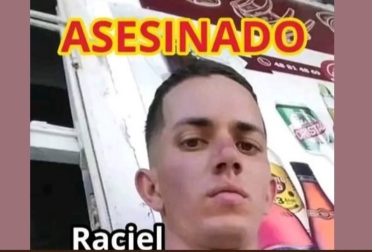 Joven posa detrás de palabras 'Asesinado' y 'Raciel'