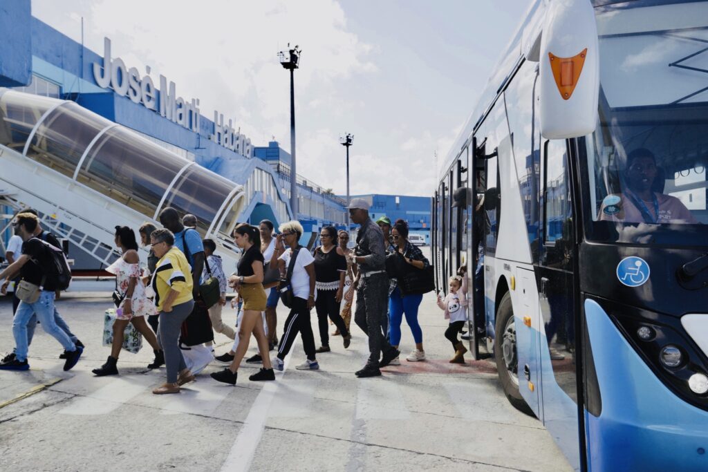 Personas descendiendo de autobús en aeropuerto José Martí