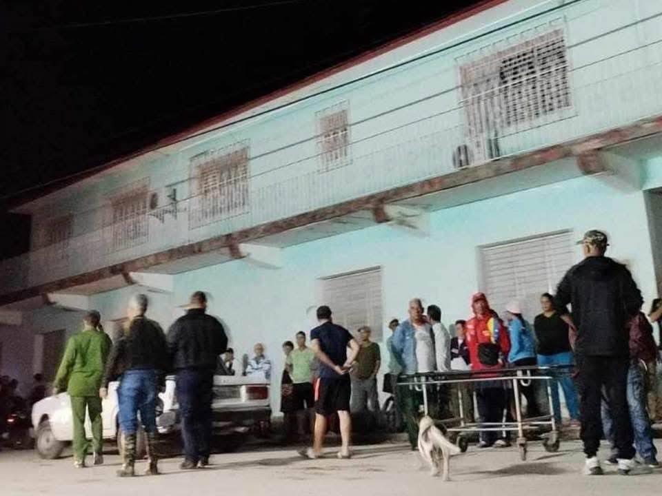 Gente reunida de noche frente a edificio con balcón