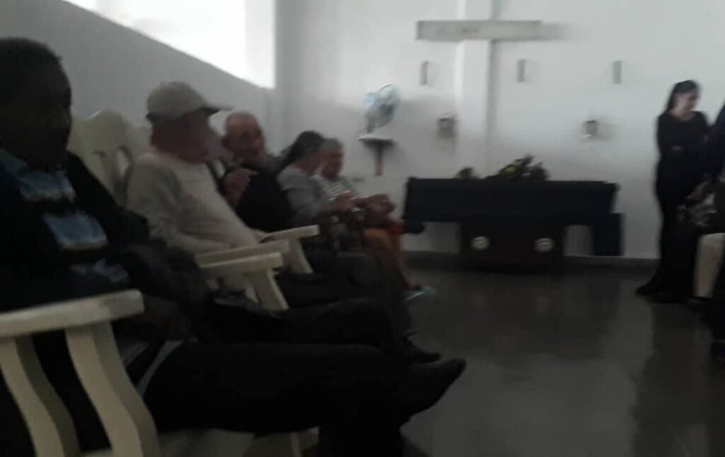 Personas sentadas en sala con cruz blanca