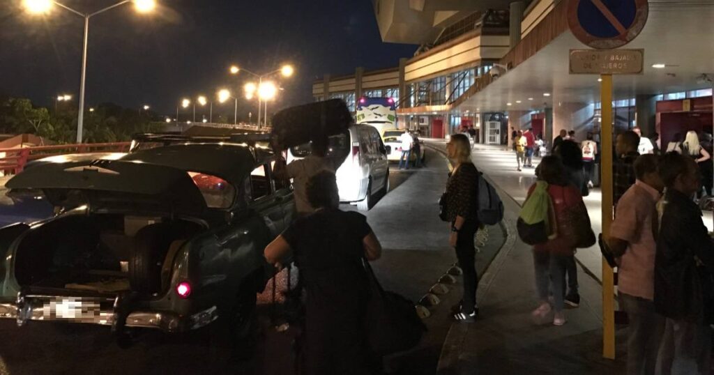 Gente junto a coches en terminal aeroportuaria nocturna