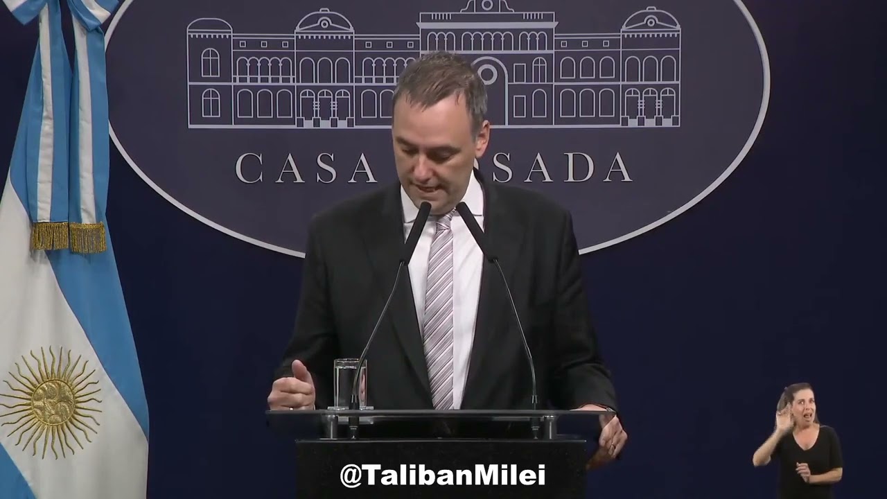 Hombre hablando en podio, intérprete de lenguaje de signos