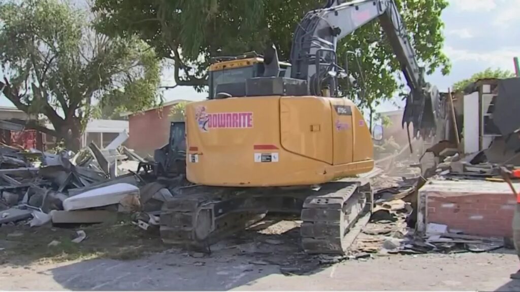 Excavadora removiendo escombros de edificio demolido